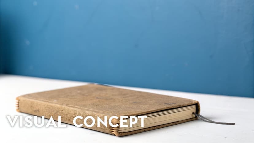 A closed brown vintage notebook with a dark string bookmark on a white desk against a blue wall.